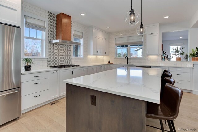 785 Delechant Dr, Erie, CO 80516 - kitchen featuring appliances with stainless steel finishes, wall chimney range hood, a breakfast bar area, decorative backsplash, and recessed lighting