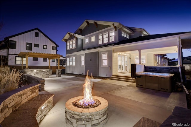 785 Delechant Dr, Erie, CO 80516 - back of house at night with an outdoor fire pit, a hot tub, and a patio