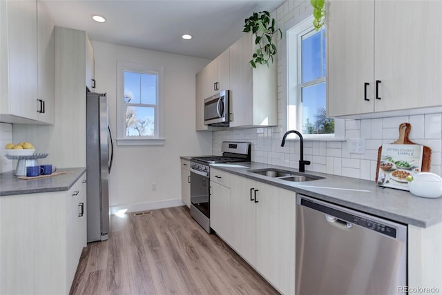 785 Delechant Dr, Erie, CO 80516 - kitchen with appliances with stainless steel finishes, light wood-style floors, backsplash, white cabinetry, and recessed lighting