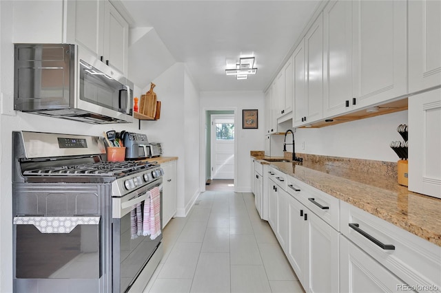 845 Jasmine St, Denver, CO 80220 - kitchen featuring stainless steel appliances, white cabinetry, light stone countertops, and light tile patterned flooring