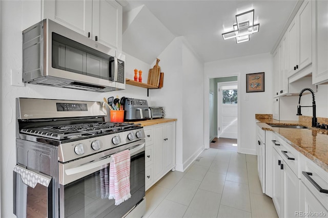 845 Jasmine St, Denver, CO 80220 - kitchen featuring appliances with stainless steel finishes, white cabinets, light stone counters, and light tile patterned floors