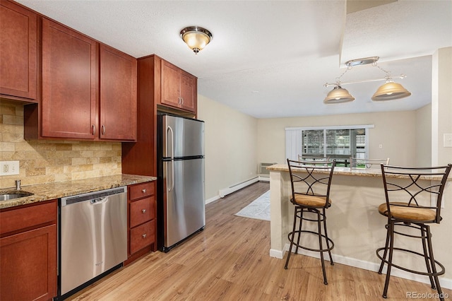 kitchen with light stone countertops, a baseboard heating unit, stainless steel appliances, and a breakfast bar area