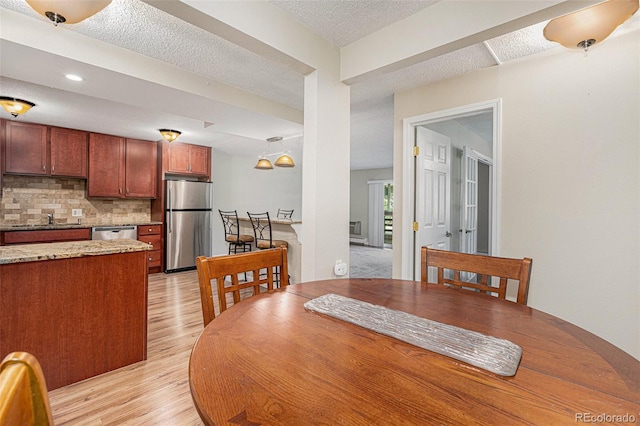 dining room featuring a textured ceiling, sink, and light hardwood / wood-style flooring