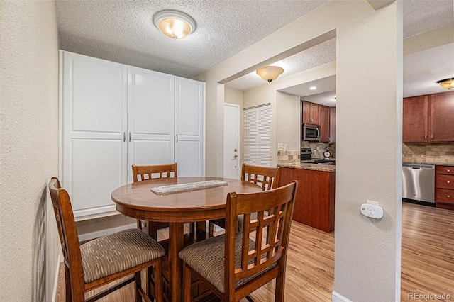 dining room with light hardwood / wood-style floors and a textured ceiling