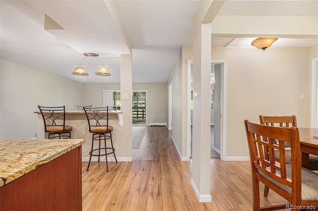 dining room featuring a textured ceiling, light hardwood / wood-style flooring, and a baseboard heating unit