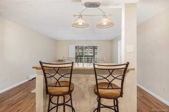 dining area featuring a textured ceiling and dark hardwood / wood-style flooring