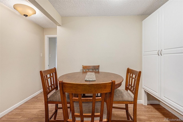 dining space with a textured ceiling and light hardwood / wood-style flooring