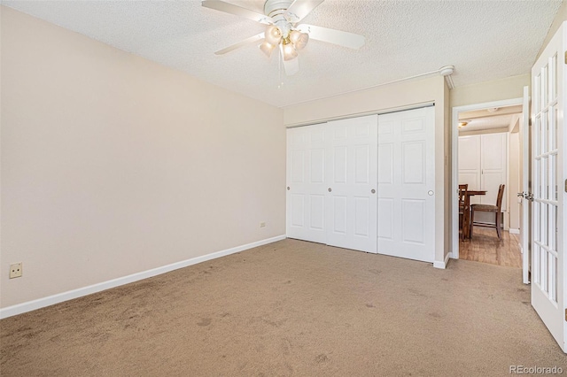 unfurnished bedroom featuring carpet flooring, a textured ceiling, a closet, and ceiling fan