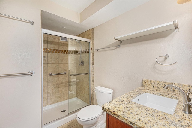 bathroom featuring tile patterned flooring, vanity, toilet, and a shower with shower door