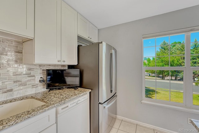 2028 Palm Dr, Colorado Springs, CO 80918 - kitchen featuring white dishwasher, backsplash, white cabinetry, light stone countertops, and light tile patterned flooring