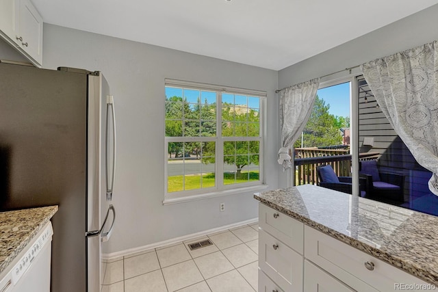 2028 Palm Dr, Colorado Springs, CO 80918 - kitchen featuring freestanding refrigerator, white cabinetry, dishwasher, light tile patterned flooring, and light stone counters