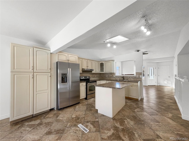 kitchen with appliances with stainless steel finishes, tasteful backsplash, sink, decorative light fixtures, and a kitchen island