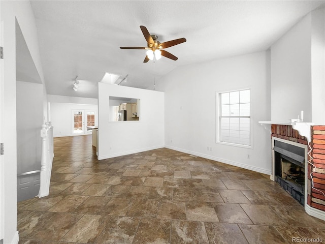 unfurnished living room with ceiling fan, vaulted ceiling, and a brick fireplace