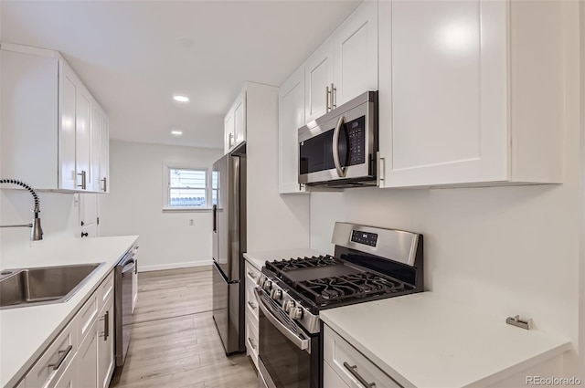 5090 Tejon St, Denver, CO 80221 - kitchen with appliances with stainless steel finishes, a sink, light wood finished floors, white cabinetry, and recessed lighting