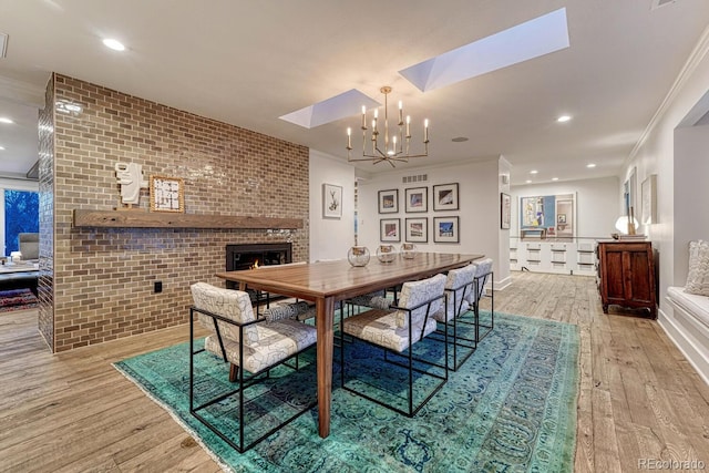 dining area featuring a skylight, crown molding, a brick fireplace, brick wall, and hardwood / wood-style flooring