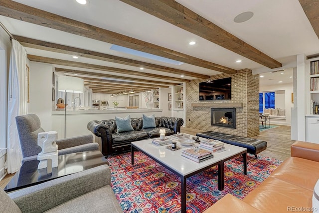 living area with built in shelves, beam ceiling, recessed lighting, a brick fireplace, and wood finished floors