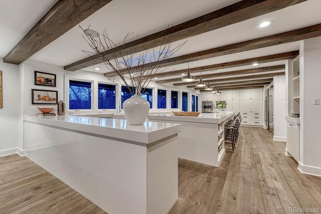 bar featuring light wood finished floors, beam ceiling, stainless steel oven, and recessed lighting