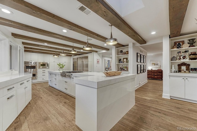 kitchen with light wood finished floors, visible vents, a large island, appliances with stainless steel finishes, and white cabinetry