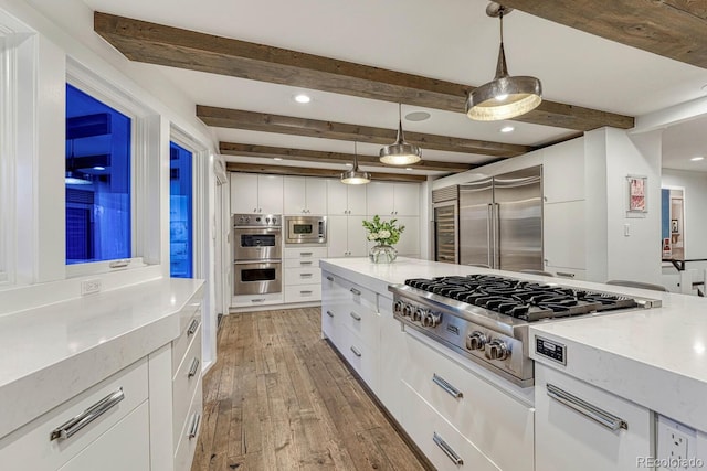 kitchen with white cabinets, built in appliances, light countertops, light wood-type flooring, and beam ceiling