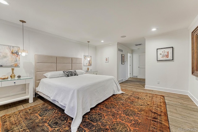 bedroom with visible vents, crown molding, baseboards, and wood finished floors