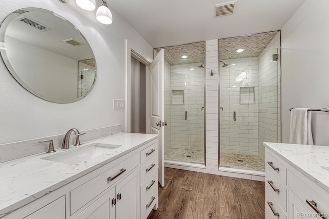 full bath featuring a shower stall, visible vents, wood finished floors, and vanity