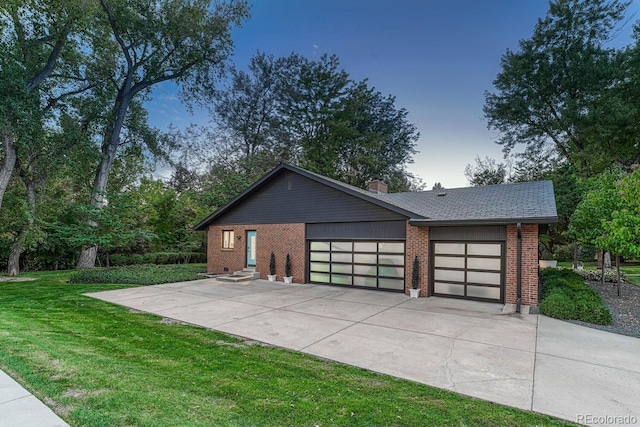 view of front of property with an attached garage, driveway, a front yard, and brick siding