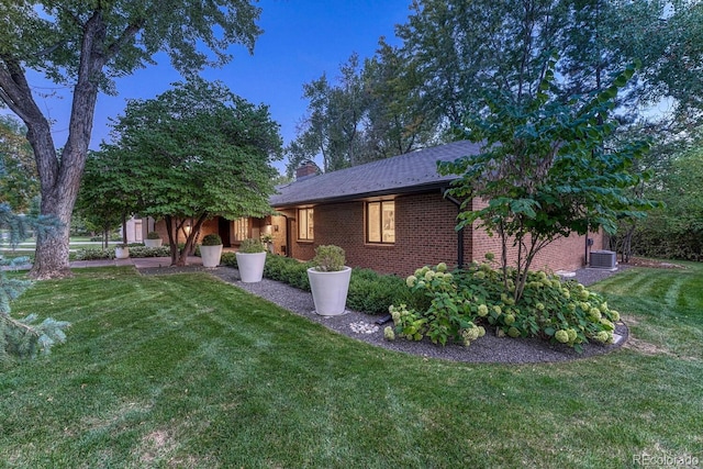 view of front of property with brick siding, a chimney, and a front lawn