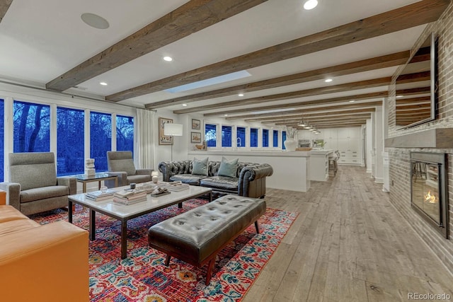 living area featuring light wood-type flooring, beam ceiling, a fireplace, and recessed lighting