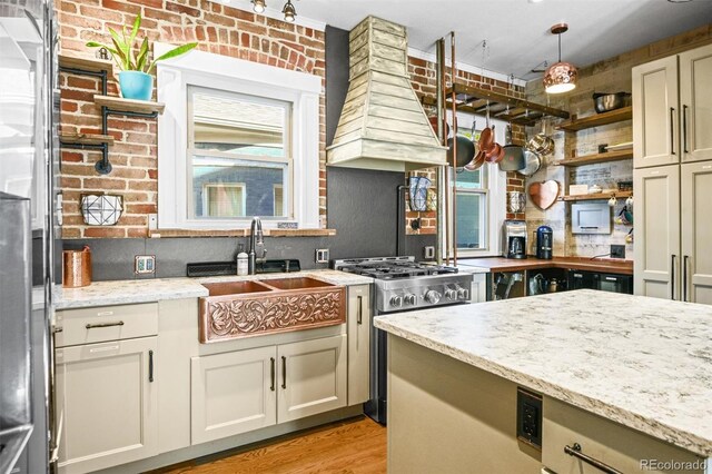 3811 N Clay St, Denver, CO 80211 - kitchen with light stone countertops, gas stove, brick wall, and premium range hood