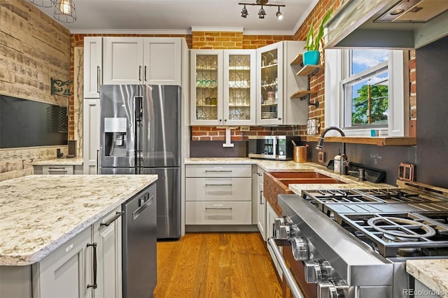 3811 N Clay St, Denver, CO 80211 - kitchen featuring light stone countertops, wood finished floors, stainless steel appliances, ornamental molding, and glass insert cabinets