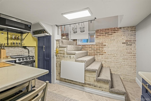 3811 N Clay St, Denver, CO 80211 - kitchen featuring blue cabinetry, light countertops, backsplash, and brick wall