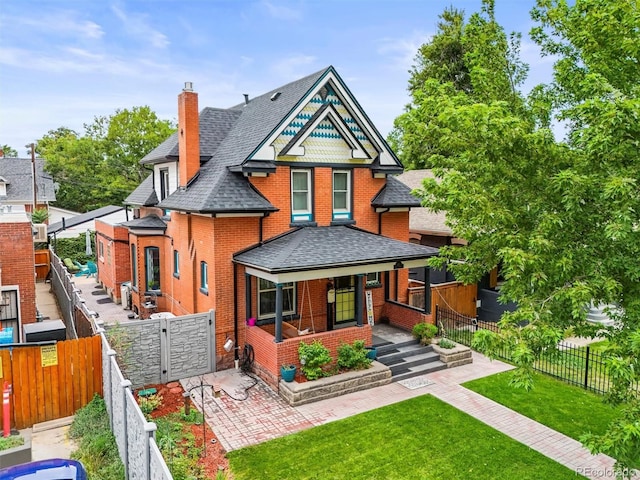 3811 N Clay St, Denver, CO 80211 - victorian house with a chimney, brick siding, a fenced backyard, a shingled roof, and a porch