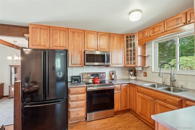 11349 Downing Dr, Northglenn, CO 80233 - kitchen featuring stainless steel appliances, backsplash, glass insert cabinets, a chandelier, and light wood-style floors