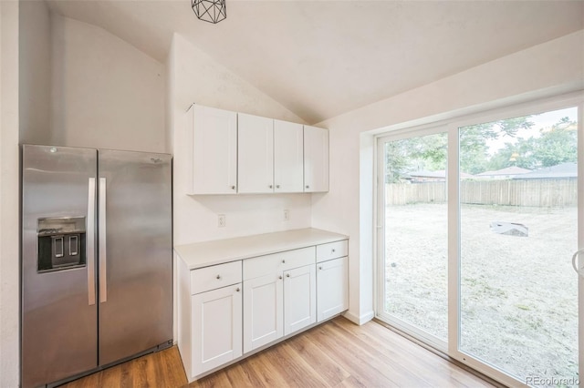 7010 W 44th Ave, Wheat Ridge, CO 80033 - kitchen with stainless steel fridge, vaulted ceiling, light wood-style flooring, white cabinetry, and light countertops