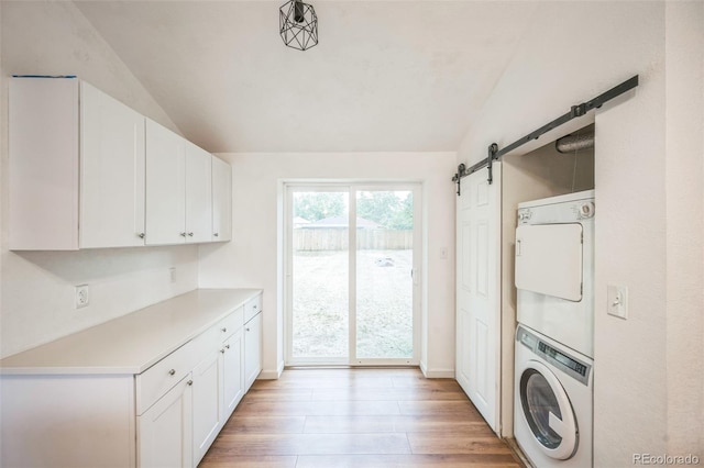 7010 W 44th Ave, Wheat Ridge, CO 80033 - laundry area with stacked washer and clothes dryer, light wood-style flooring, and a barn door
