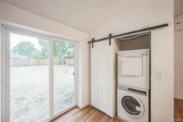 7010 W 44th Ave, Wheat Ridge, CO 80033 - laundry area featuring stacked washer / drying machine, a barn door, and light wood-style floors