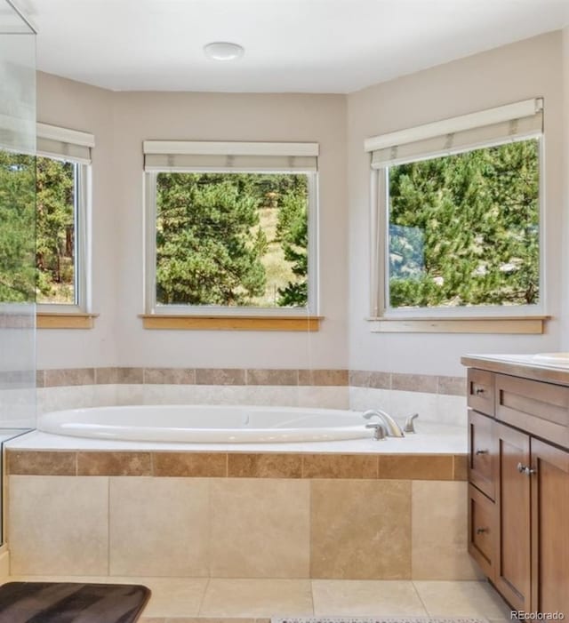 bathroom with tile patterned flooring, vanity, and tiled bath