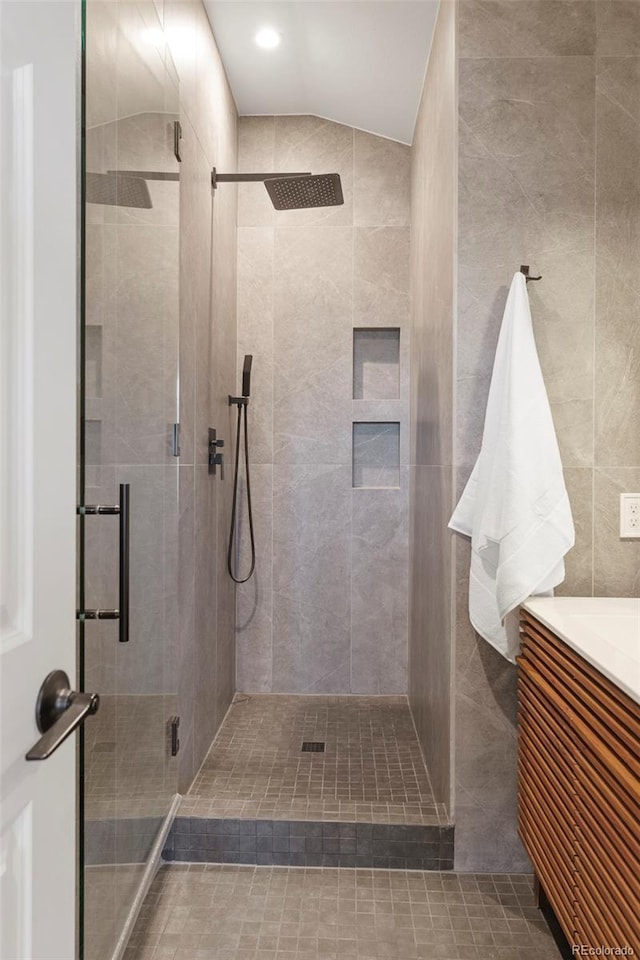 bathroom featuring vanity, a shower with shower door, and lofted ceiling