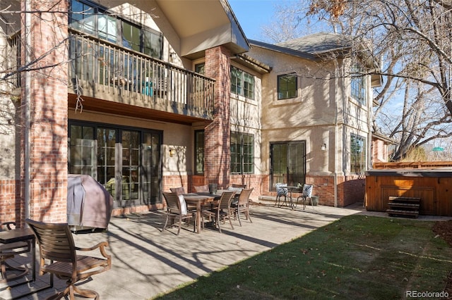 back of house featuring a balcony, a patio, and a hot tub