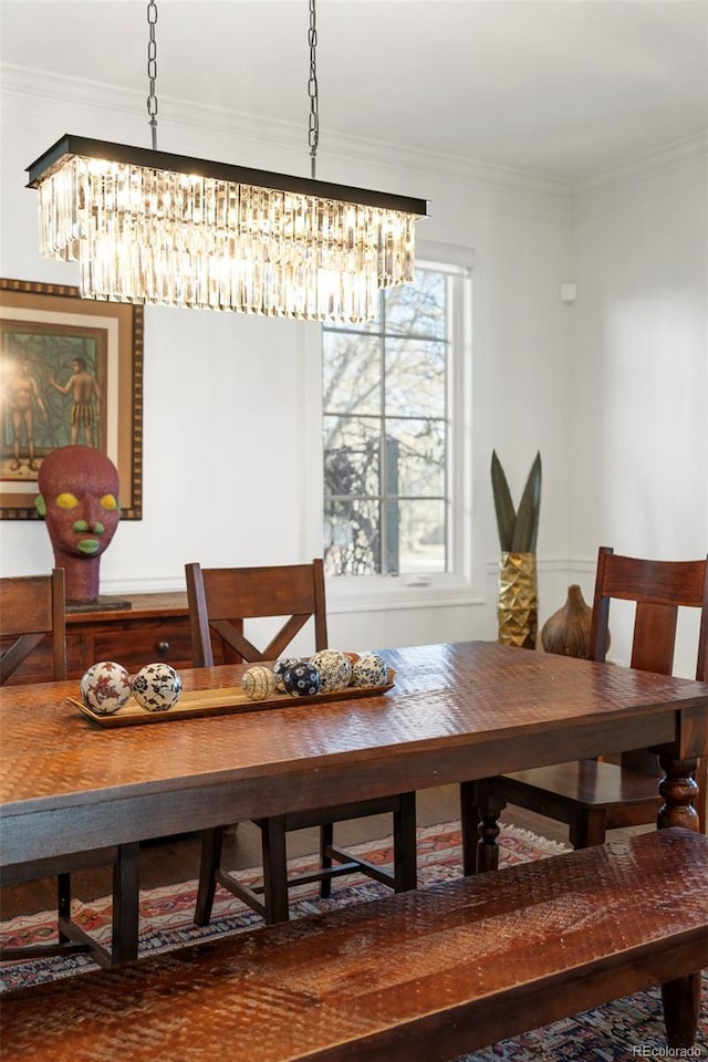 dining space with crown molding, plenty of natural light, and an inviting chandelier