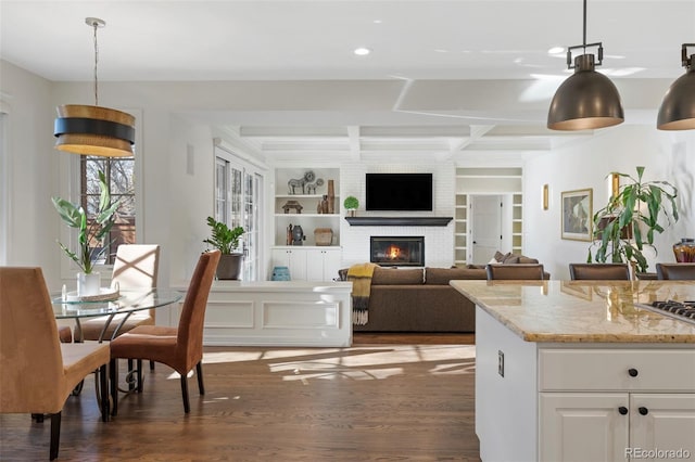 dining space featuring built in shelves, a fireplace, beamed ceiling, and dark hardwood / wood-style floors