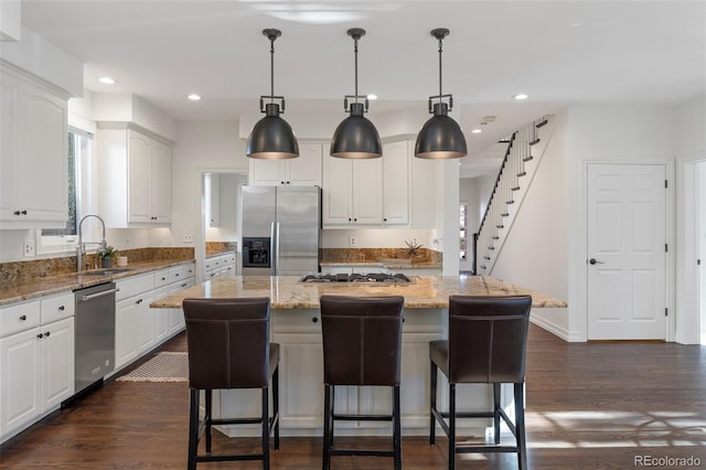 kitchen featuring white cabinetry, a kitchen island, light stone counters, and appliances with stainless steel finishes