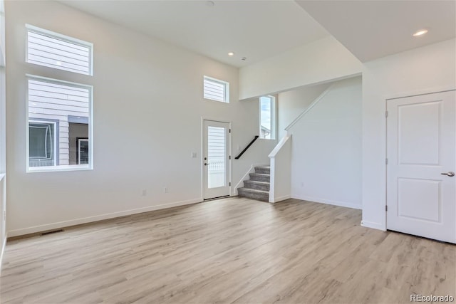 interior space featuring a towering ceiling and light hardwood / wood-style floors