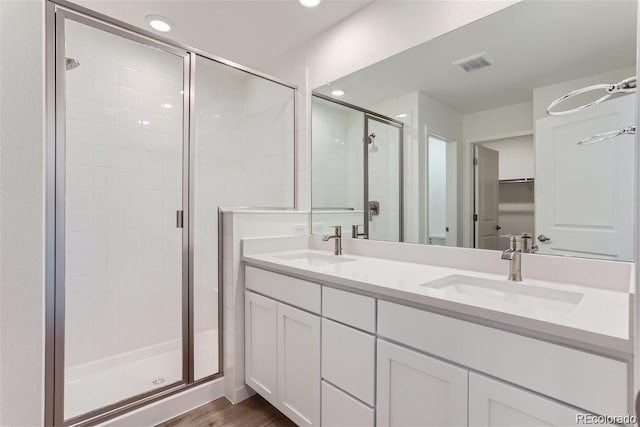 bathroom with a shower with door, vanity, and wood-type flooring