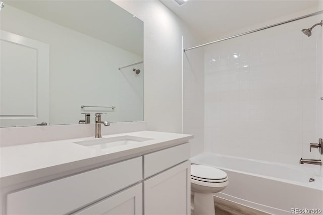 full bathroom with vanity, wood-type flooring, tiled shower / bath combo, and toilet