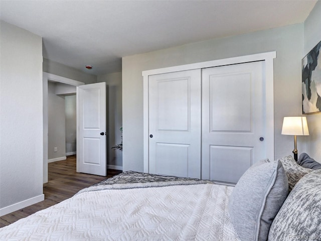 bedroom with dark wood-style flooring, a closet, and baseboards