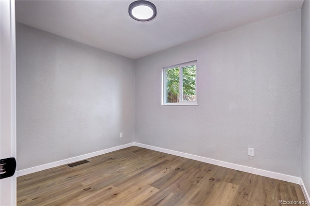 empty room featuring visible vents, baseboards, and wood finished floors