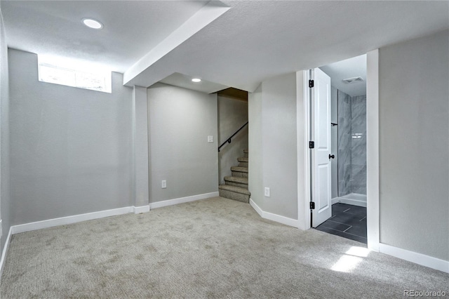 below grade area featuring stairway, dark carpet, visible vents, and baseboards