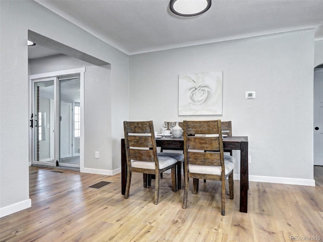 dining area with wood finished floors, visible vents, and baseboards