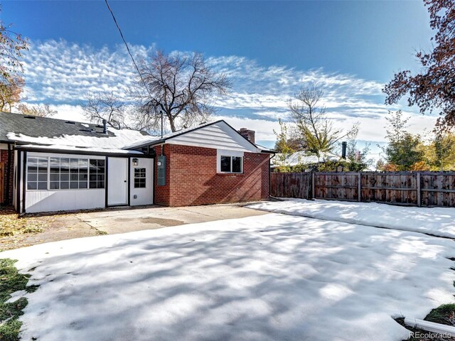 exterior space featuring a chimney, fence, and brick siding